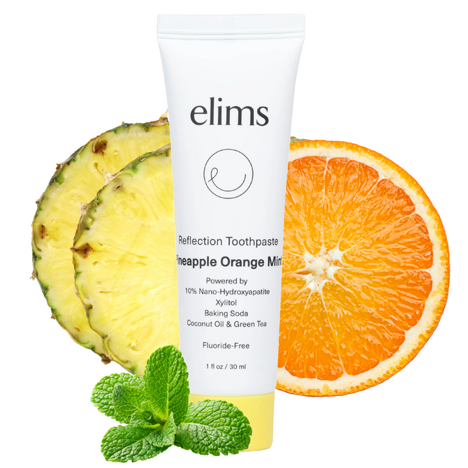 elims pineapple orange mint toothpaste set in front of a slice of orange and pineapple and mint