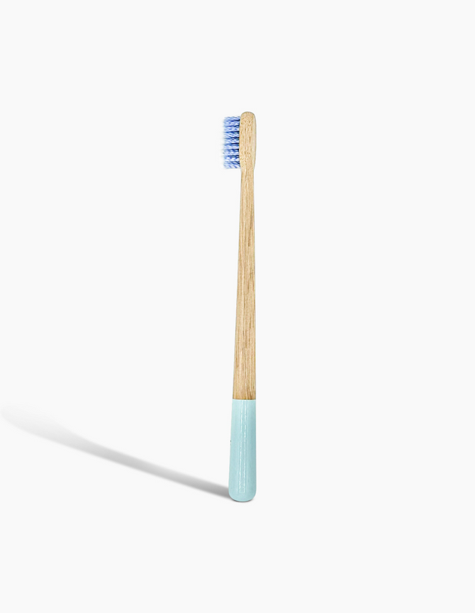A sustainable bamboo toothbrush with a blue-dipped handle and soft bristles, branded with the 