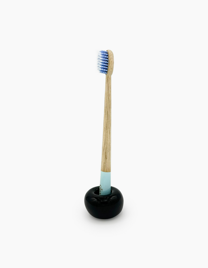 A sustainable bamboo toothbrush with a blue-dipped handle and soft bristles, branded with the 