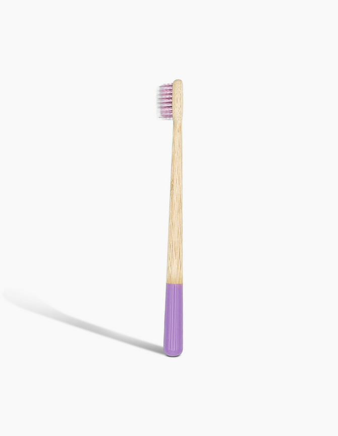 A sustainable bamboo toothbrush with a purple-dipped handle and soft bristles, branded with the 