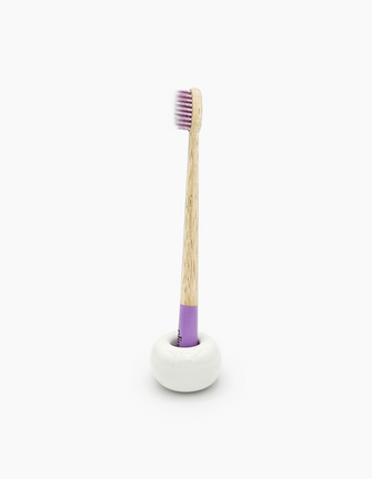 A sustainable bamboo toothbrush with a purple-dipped handle and soft bristles, branded with the 